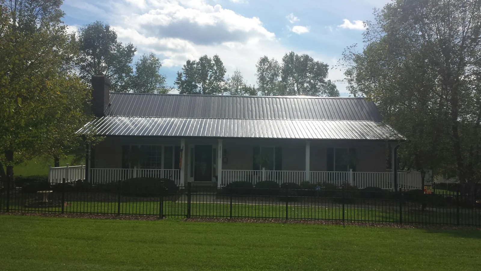 Gray metal roof on a brick ranch with a full width front porch — Gutter Guard Installation work by our crew in Bluffton